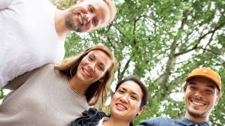 Ryhmä iloisia ihmisiä kesällä ulkona.